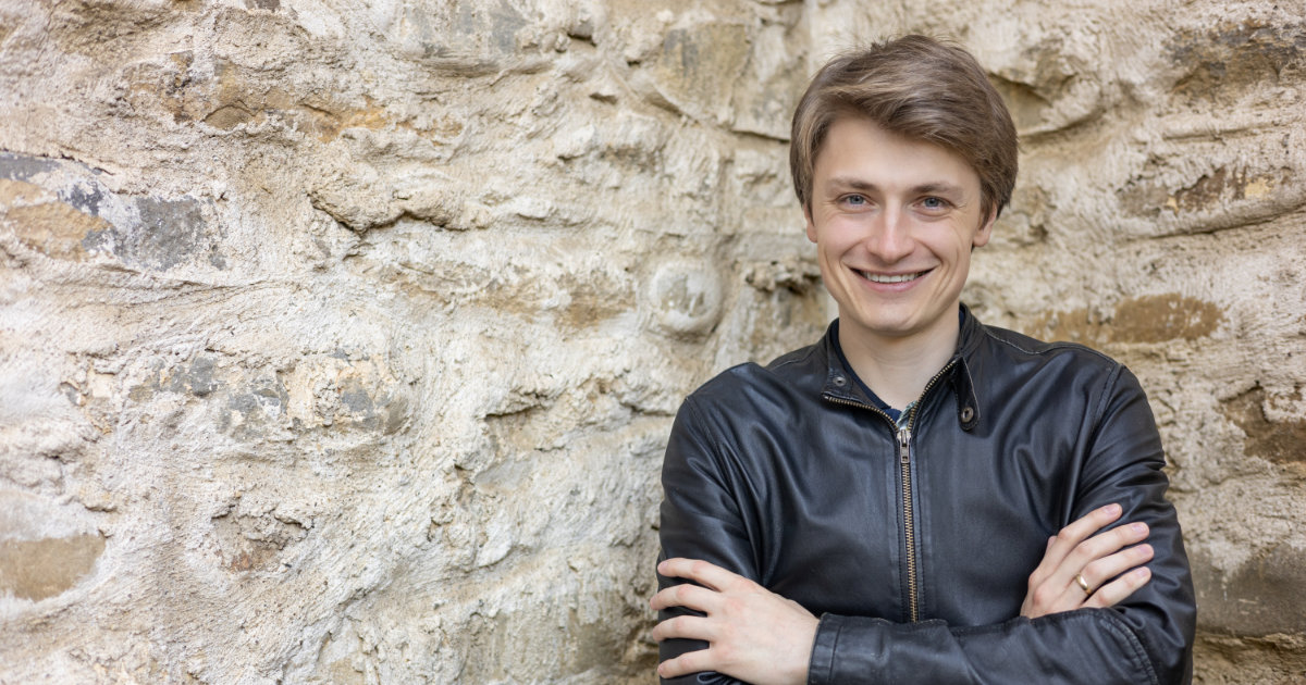 Patric Pförtner next to a stone wall